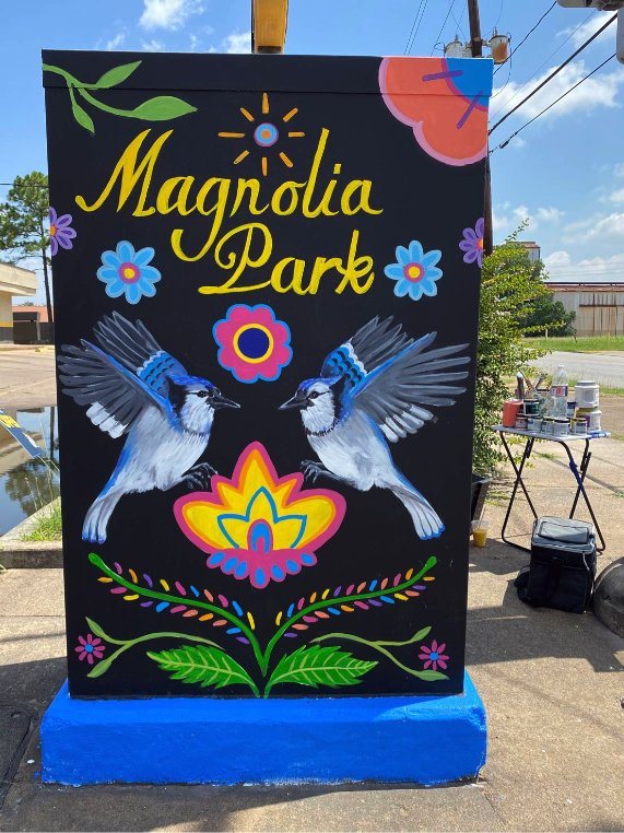 Black utility box painted with two blue jays, folk flowers and the words Magnolia Park