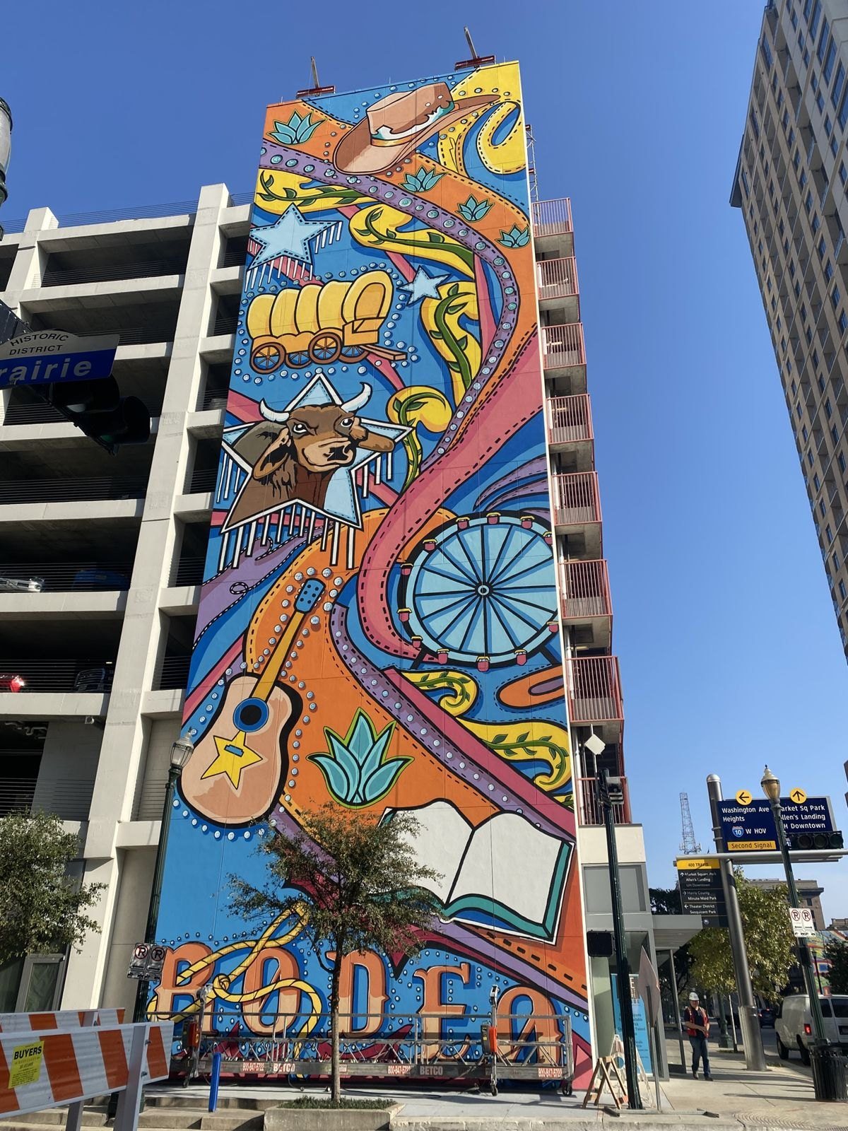 Towering rodeo mural of a cowboy on a bucking horse painted on a high-rise wall