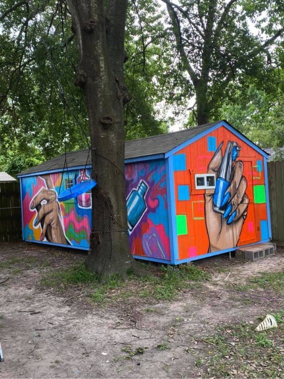 Backyard studio building wrapped in a bright mural of hands holding nail polish bottles