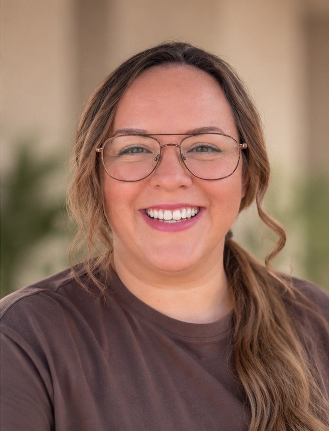Sylvia Blanco, founder and artist of Blanco Art, smiling in glasses and a brown shirt